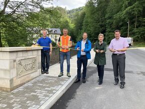 Personen auf Brücke mit Band in der Hand und Scheren