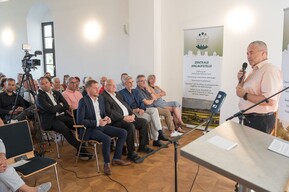 Gruppe von Personen sitzt vor einer Person und hört zu