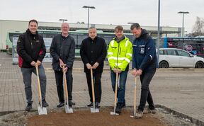 Männer halten einen Spaten als Symbol für den Spatenstich in die Erde