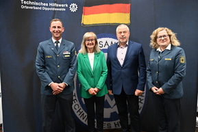 vier Personen vor Leinwand des THW