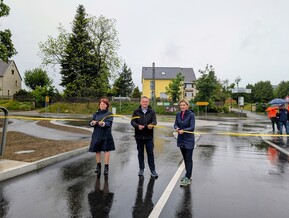 drei Personen schneiden Band durch im Regen
