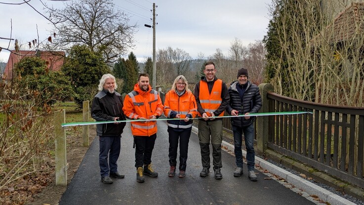 Fünf Personen durchschneiden ein Band zur Einweihung des Anliegerweges