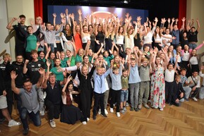 Gruppe an Personen räckt die Hände in die Höhe