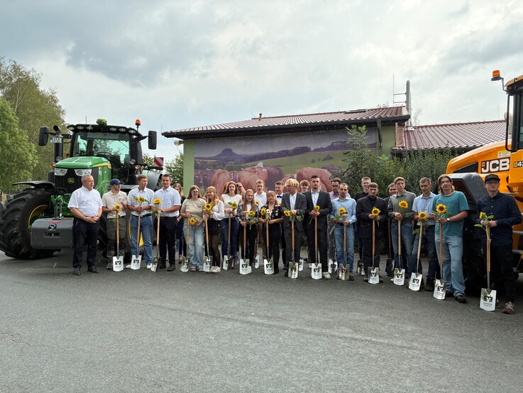 Jungfacharbeiter mit Landrat am Traktor stehend mit Sonnenblume in der Hand