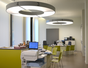 Bürotische mit grünen Stühlen und runden Leuchten an der Decke