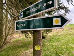 Wegweiser in Wald mit gelbem Notrufpunkt