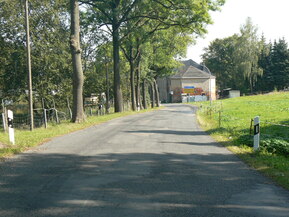 Straße mit Bäumen und Haus am Ende
