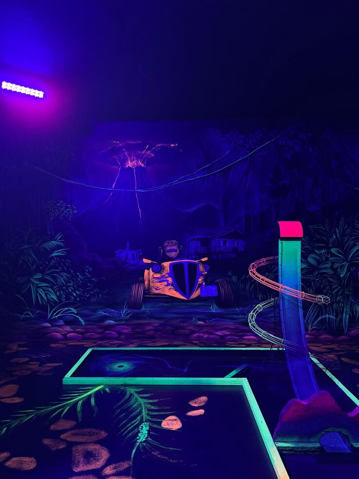 Zu sehen ist der Innenbereich ener Schwarzlicht-Minigolfanlage.