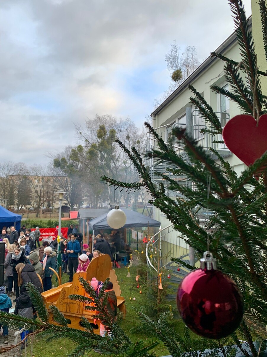 Garten eines öffentlichen Gebäudes mit Grillbude und Besucherinnen/Besuchern zum sozialen Weihnachtsmarkt auf dem Sonnenstein