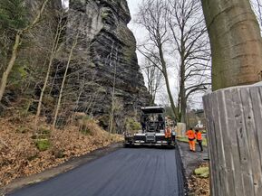 Hintergrund Sandstein Vordergrund frisch gemachte Straße mit Planierraupe und Bauarbeitern