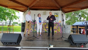 drei Menschen stehen auf einer Bühne und sprechen ein Grußwort 