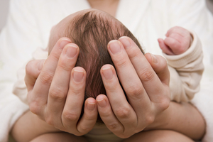 Hände halten einen Babykopf