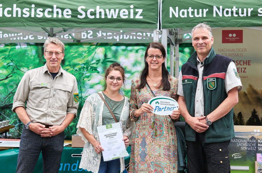 Uwe Borrmeister, Hanspeter Mayr und die Familie Biedermann der "Urlaubsfreude" Ostrau vor einem Stand der Nationalparkverwaltung